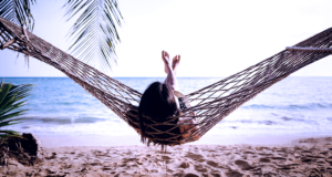 Mujer descansa en una hamaca en la playa